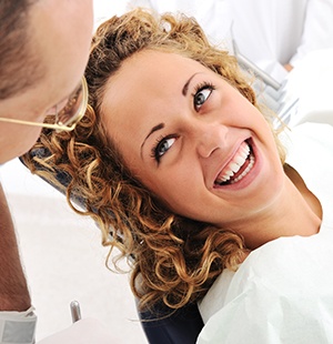 curly haired woman smiling up at dentist 