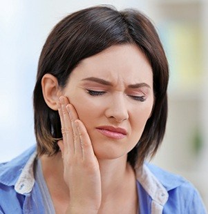 woman holding cheek in pain