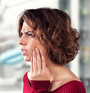 woman in red sweater holding jaw