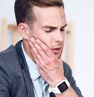 man with white watch on holding his jaw